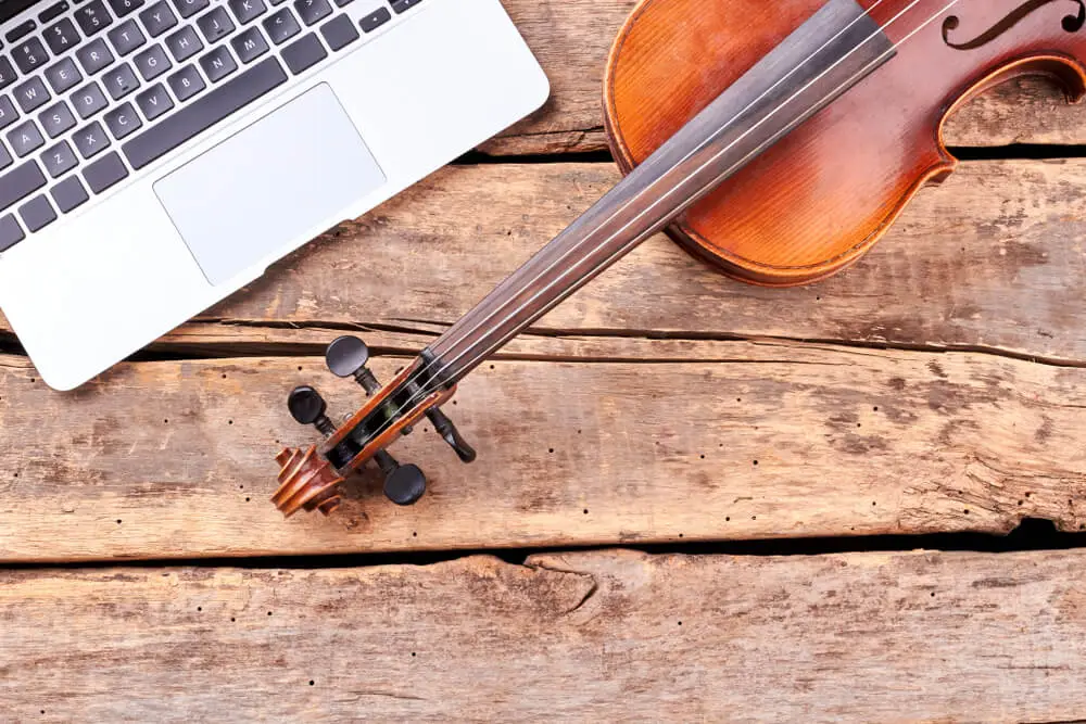 Foto que describe un violín y un ordenador encima de una mesa. 5 consejos para tus clases de música online